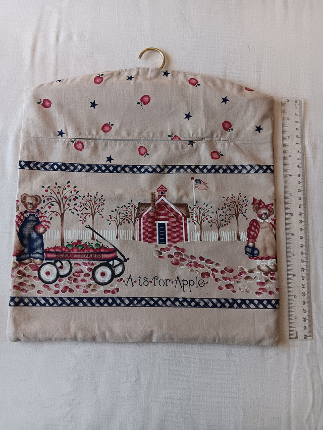 Hand made Peg Bag with wooden coat hanger. Apples print fabric with a wide picture border and plain beige lining. 