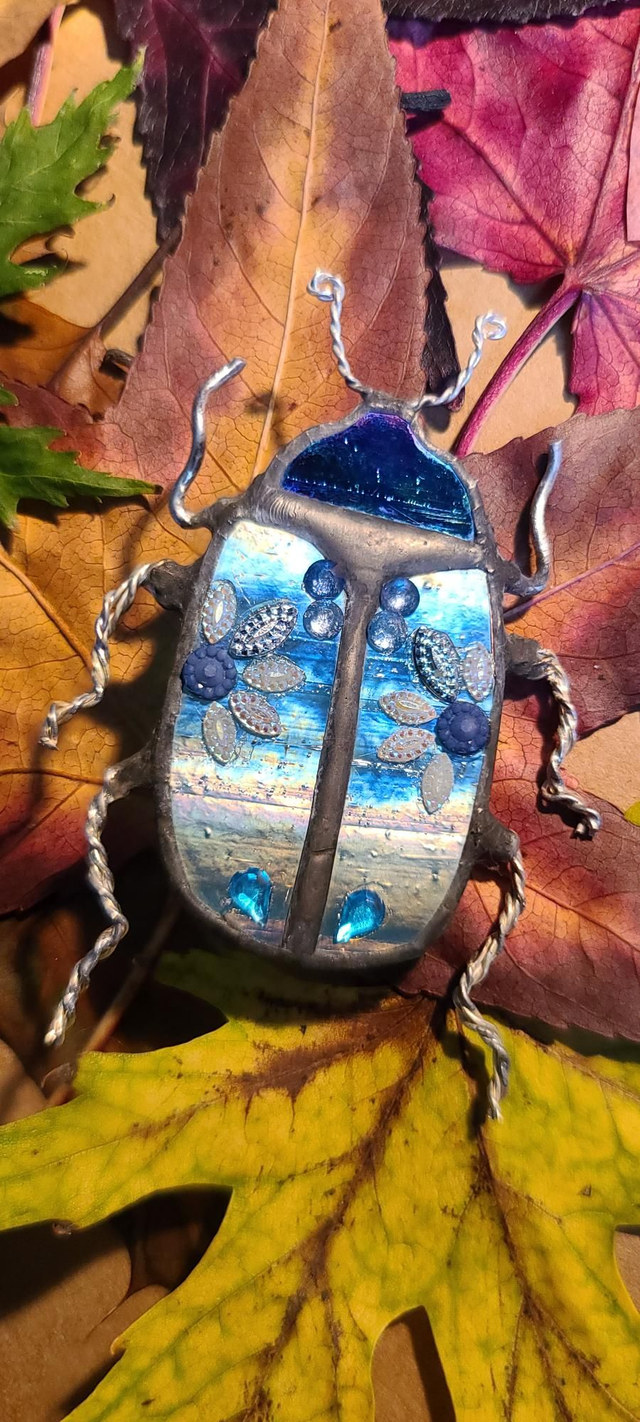 Scarabée en Tiffany, au corps bleu iridescent et à la tête noire, monté en broche. 