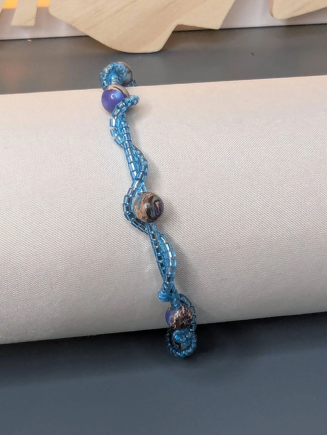 Bracelet torsadé bleu, avec des perles Miyuki en verre et des perles naturelles montées sur fil de fer. Le fermoir est de couleur argent.