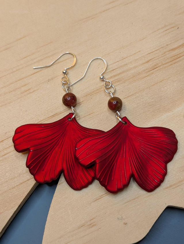 Boucles d'oreilles pendentifs en forme de feuilles, de couleur rouge métallisé avec des perles de cloisonne rouge et marron. 