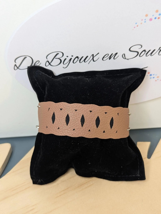 Bracelet manchette en cuir marron clair, avec du tissus enduit noir (résistant), une chaine couleur argent. Le fermoir est  de couleur argent.