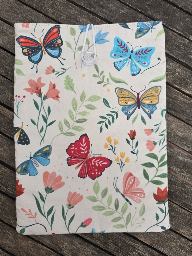 Funda de libro acolchada de mariposas de colores, fondo blanco roto