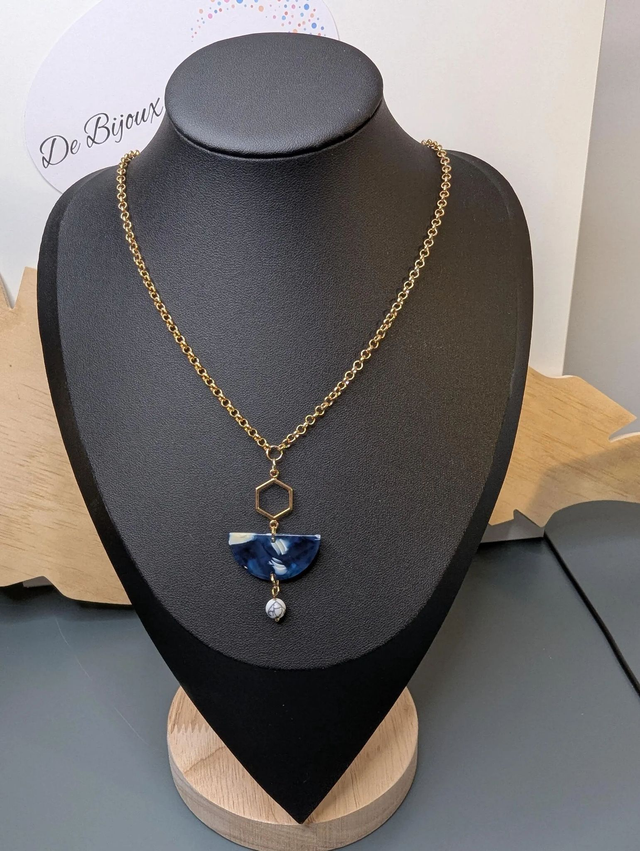 Collier mi long avec une chaine de couleur or et un pendentif en résine bleu et blanc, et un pendentif en métal doré. 