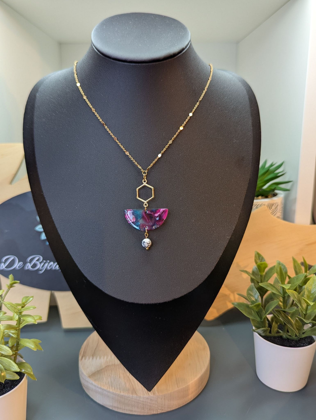 Collier mi long avec une chaine de couleur or et un pendentif en résine rose et bleu et un pendentif en métal doré.