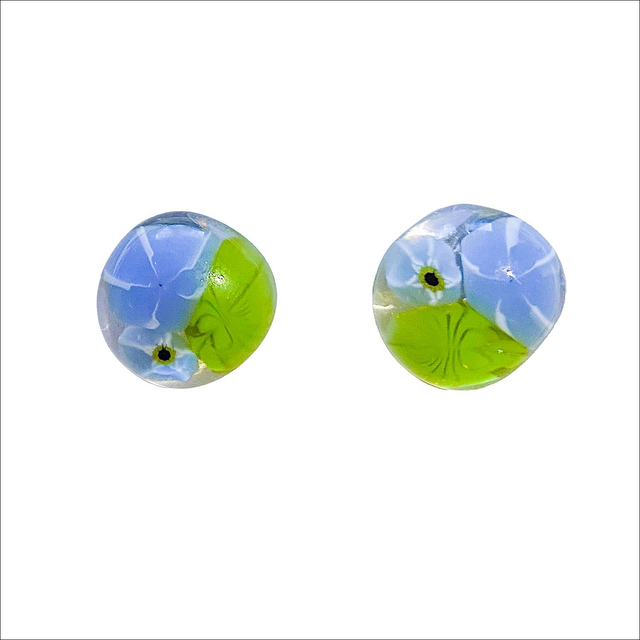 Stud earrings in fused glass in a clear background with 2 pale blue and one green murine flowers (Ref ESS7)