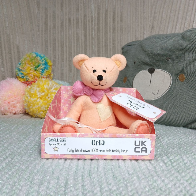 Orla. Small size, handmade teddy bear. UKCA. Tray base packaging. Standard Wool Felt. Peach. Pastel orange. Pink. Yellow.