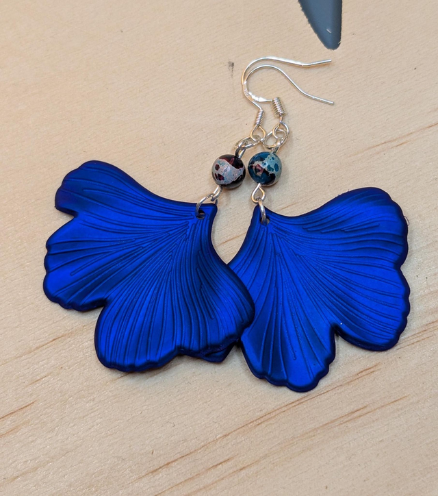 Boucles d'oreilles avec pendentifs en forme de feuilles de couleur bleu métallisé et des perles de jaspe sédiment de mer. 