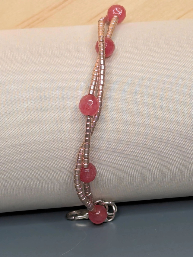 Bracelet torsadé rose métallisé, avec des perles Miyuki en verre et des perles naturelles sur fil de fer. Le fermoir est de couleur argent.