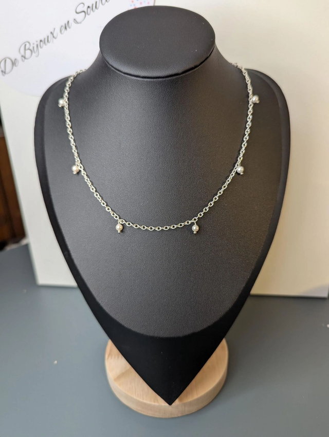 collier court avec une chaine en argent fine et des perles naturelles de coquillage blanc, la chaine fermoir est de couleur argenté. 