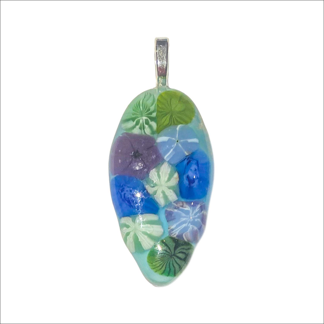 Pendant with a translucent/pale blue background and a selection of murine flowers in fused glass (Ref P31)