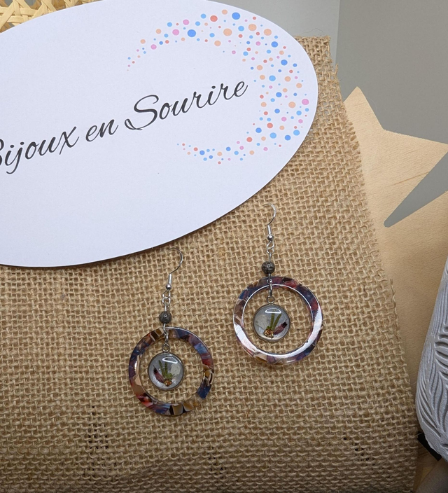 Boucles d&#039;oreilles avec 2 pendentifs en cercle en résine coloré rose et violet, avec des fleurs, et des perle naturelle, le fermoir est en argent. 