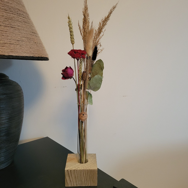 Décoration fleurs séchées dans tube à essai posé sur socle en bois