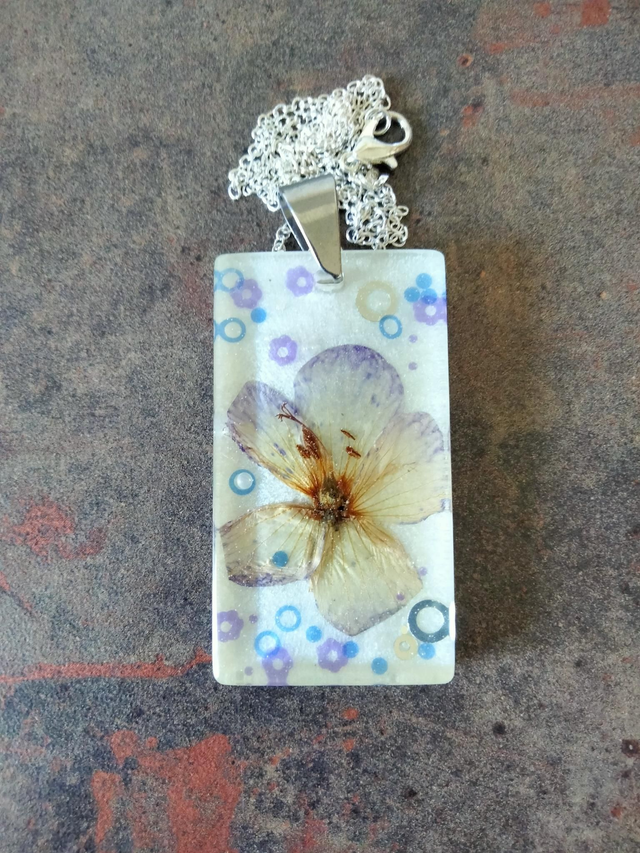 Pendentif en résine époxy fond blanc glossy avec inclusion d'une fleur séchée