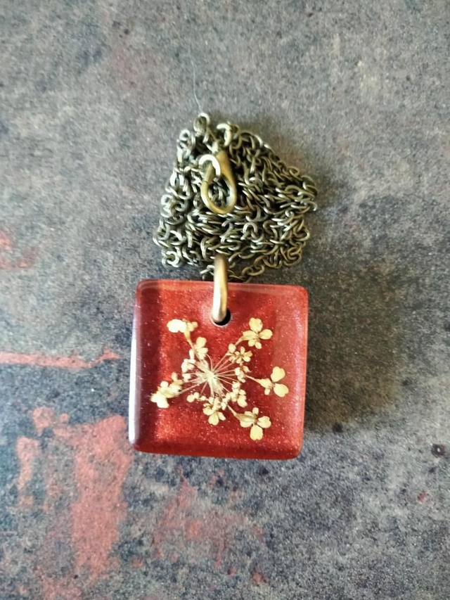 Pendentif en résine époxy couleur rouge bordeaux avec inclusion d'une fleur séchée de carotte sauvage 
