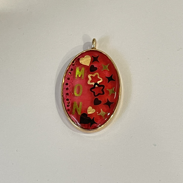 Pendentif ovale doré MON avec incrustation de cœurs et d’étoiles, fond rouge/rosé