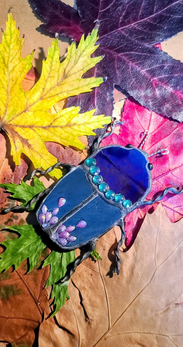 Scarabée en verre, au corps argenté et à la tête bleu iridescent,  en Tiffany et monté en magnet. 