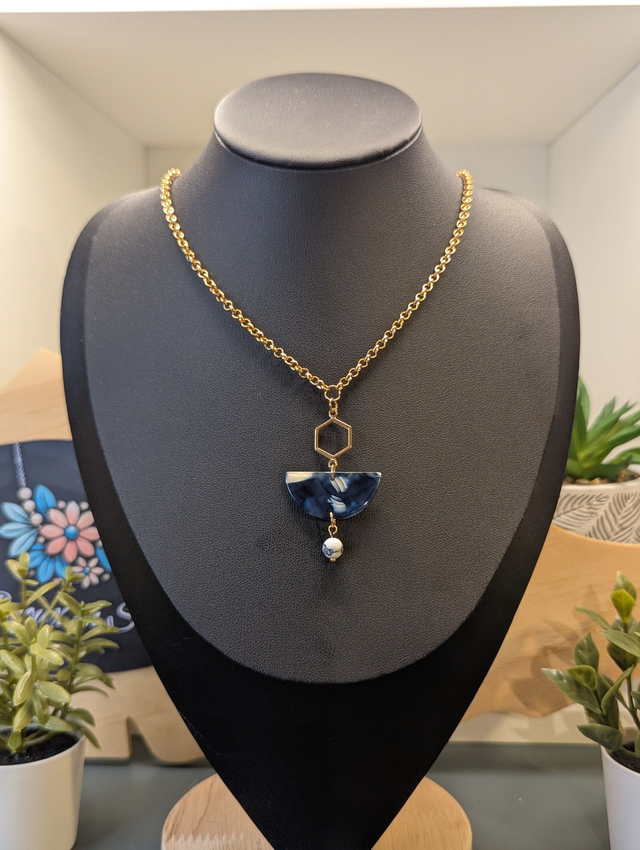 Collier mi long avec une chaine de couleur or et un pendentif en résine bleu et blanc et un pendentif en métal doré.