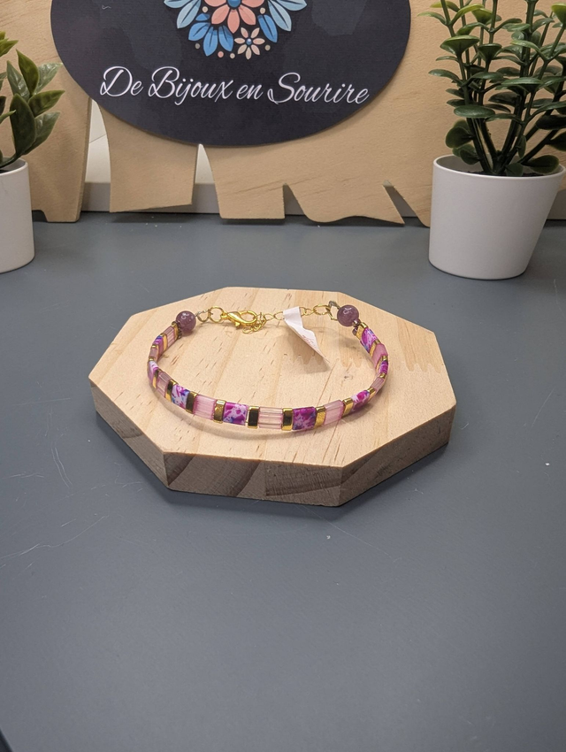 Bracelet avec des perles plate en verre rose et des perles d'espacement en métal doré. Le fermoir et la chaine fermoir sont en or.