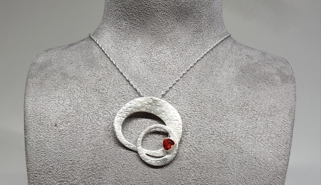 Orbital ring pendant with a deep orange cubic zirconia on silver necklace