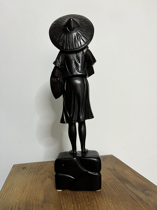 Wooden statue of a Filipino female farmer, with a hat, holding harvested rice.