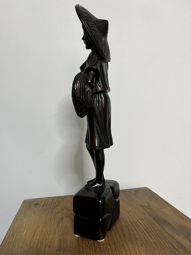 Wooden statue of a Filipino female farmer, with a hat, holding harvested rice.