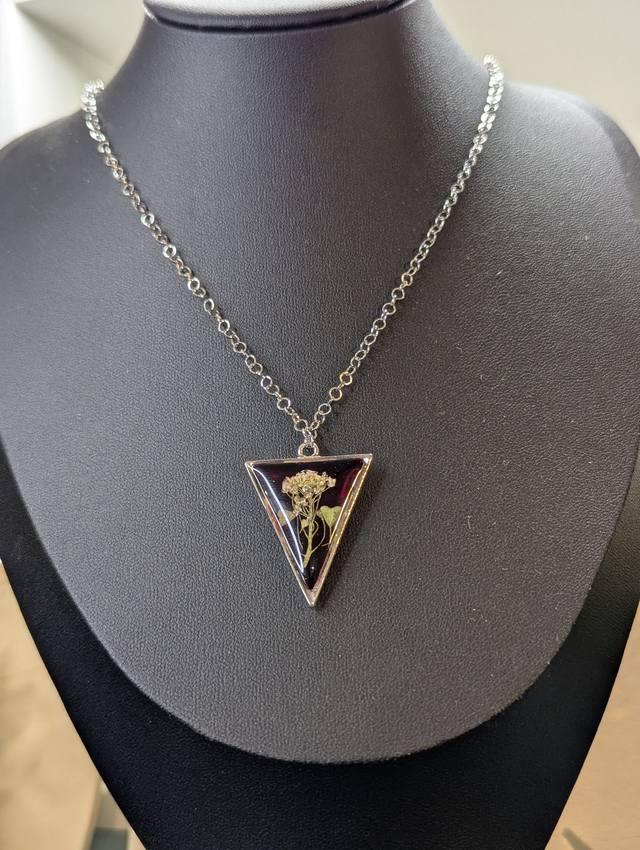 collier mi long de couleur argent avec un pendentif en résine rouge et fleur naturelle blanche. 