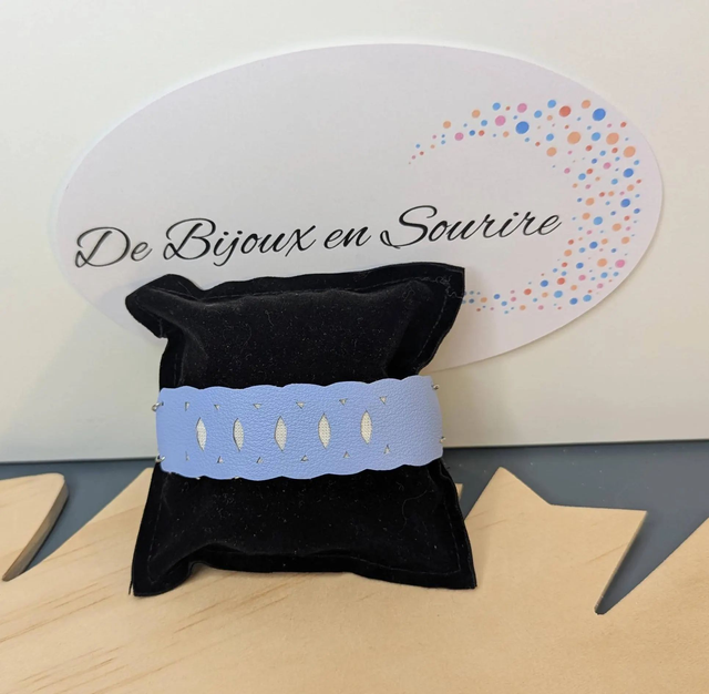 Bracelet manchette en cuir bleu lisse, avec du tissus enduit blanc (résistant), une chaine couleur argent. Le fermoir est de couleur argent.