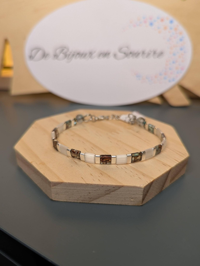 Bracelet en perles plate en verre blanc avec des  perles d'espacement en métal argenté. Le fermoir et la chaine fermoir sont en argent.