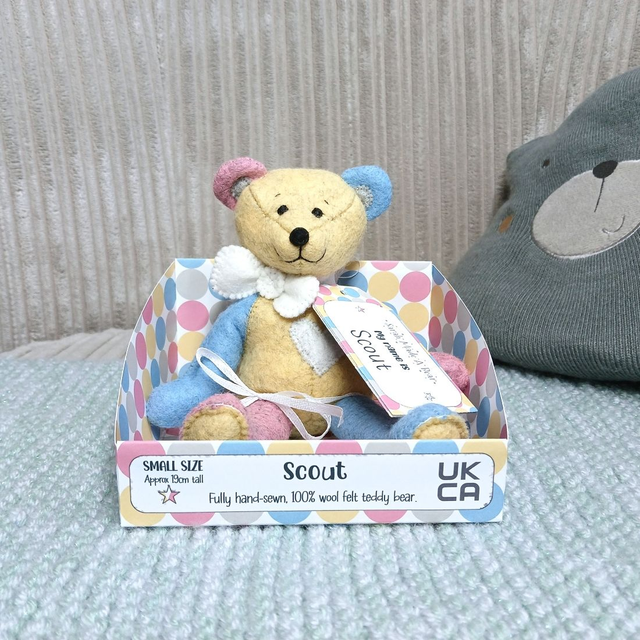 Scout. Small size, handmade teddy bear. UKCA. Tray base packaging. Standard Wool Felt. Yellow. Blue. Grey. Pink. White.