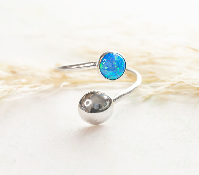 Anillo cruzado de plata 925 con casquilla brillante y un ópalo azul redondo.