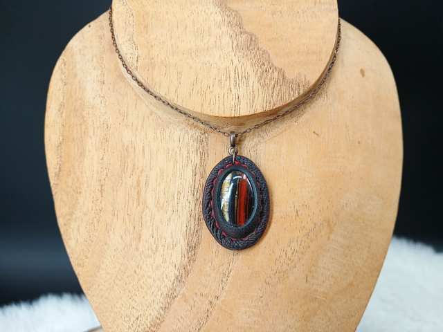 Andarta, pendentif en œil de fer et cuir