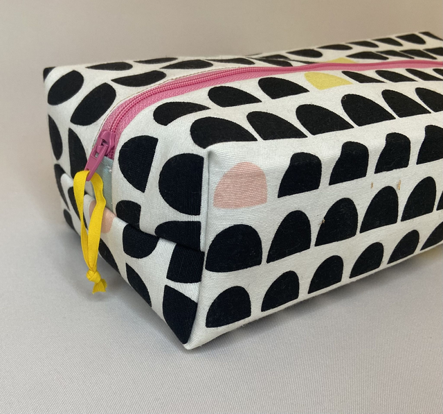 TROUSSE DE TOILETTE FUN AVEC SON ZIP ROSE ET SES MOTIFS GÉOMETRIQUES NOIRS ET PASTELS