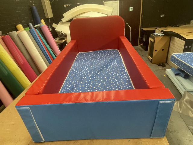 Single mattress sized bed surround with higher head board Red and Blue