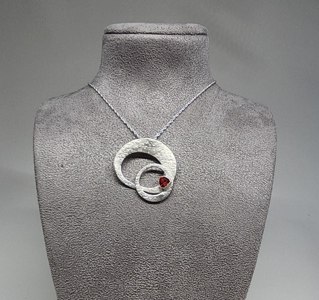 Orbital ring pendant with a deep orange cubic zirconia on silver necklace