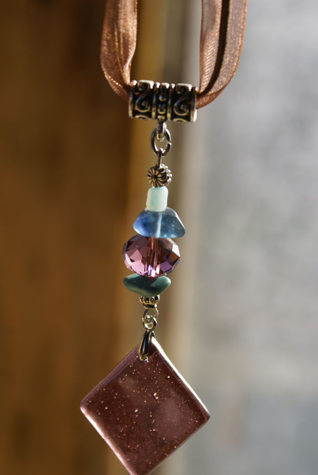 Pendentif en verre prune et chaîne en coton brun. 