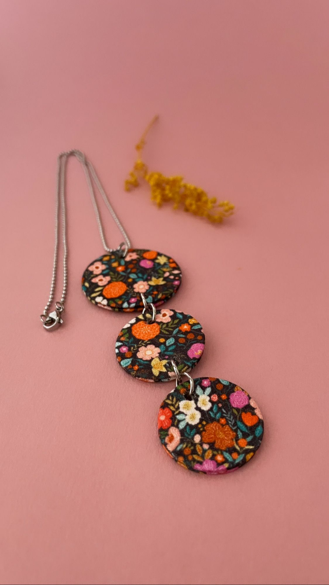 Collier avec pendentif en carton et tissu fleuri, composé de trois cercles, collection "1001 fleurs", fond noir et motifs fleuris multicolores