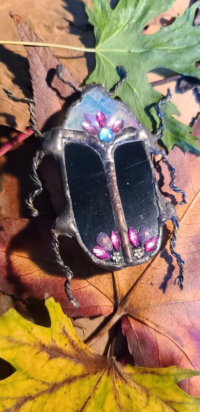 Scarabée en verre, au corps noir et à la tête blanche iridescente, en Tiffany monté en broche. 