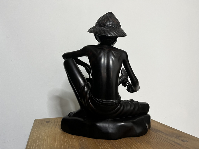 Wooden sculpture of a man feeding a rooster from Tantra Mas Bali Gallery.