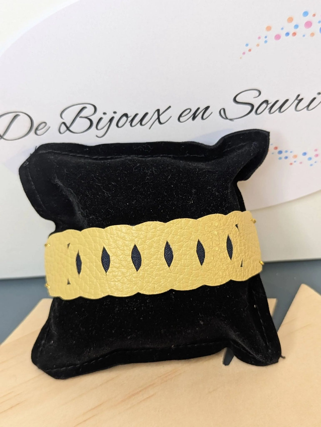 Bracelet manchette en cuir jaune, avec du tissus enduit bleu sombre (résistant), une chaine couleur or. Le fermoir est de couleur or.