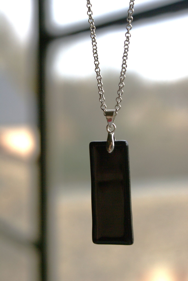Pendentif en verre noir et chaîne couleur argent.