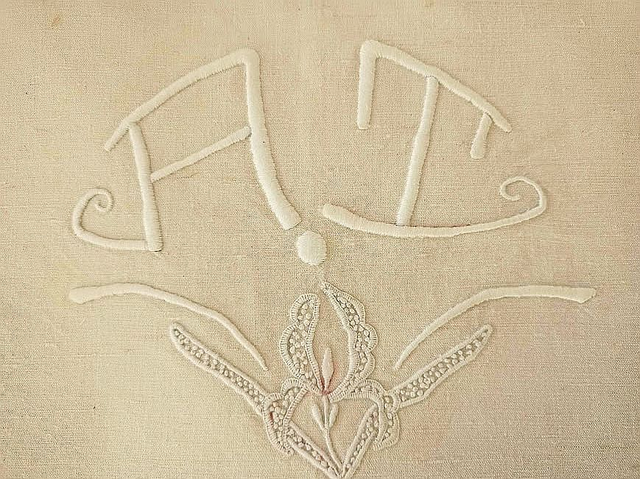 Monogramme AT sur drap beige avec jour échelle