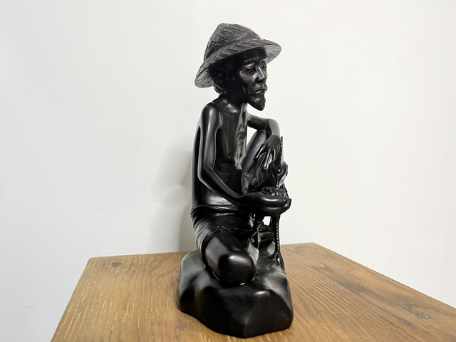Wooden sculpture of a man feeding a rooster from Tantra Mas Bali Gallery.