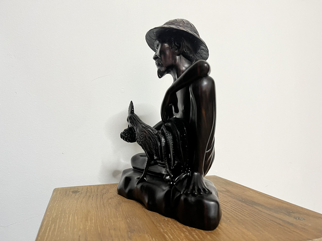 Wooden sculpture of a man feeding a rooster from Tantra Mas Bali Gallery.