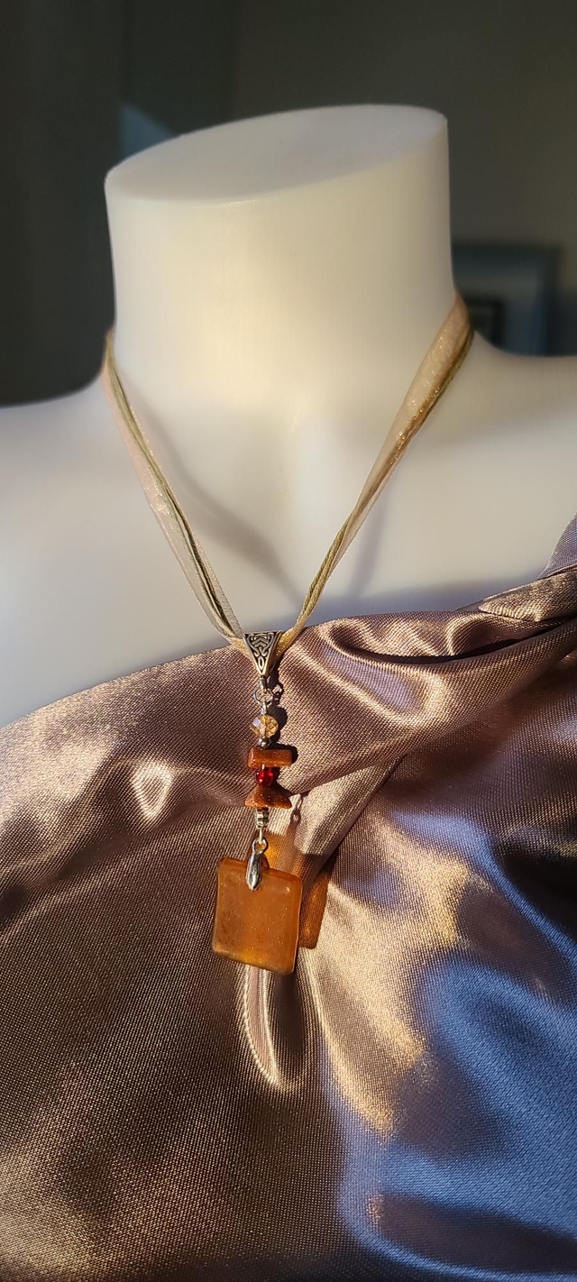 Pendentif en verre caramel dépoli et chaîne en coton brun.