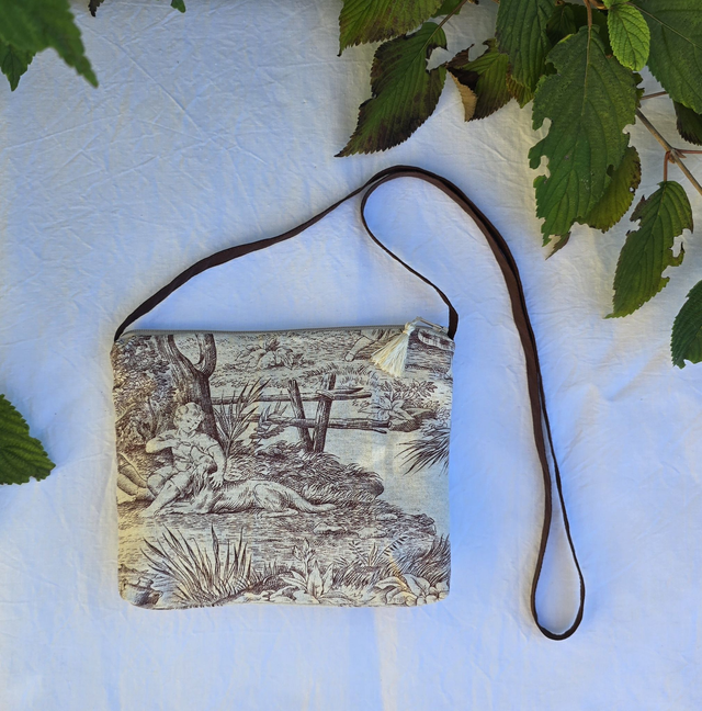 Pochette avec bandoulière en tissu toile de Jouy, agrémentée d'un pompon