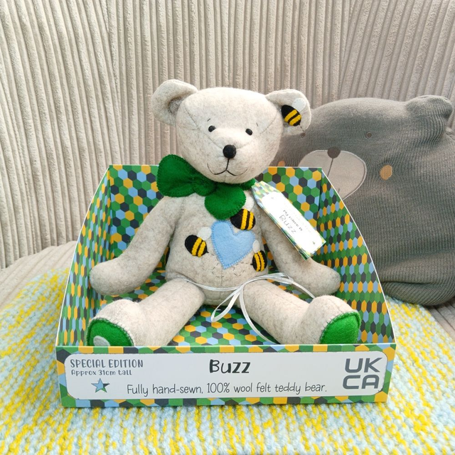 Buzz. Special Edition size, handmade teddy bear. UKCA. Tray base packaging. Standard Wool Felt. Bee pattern added. Beige. Green. Blue. Yellow. Black.