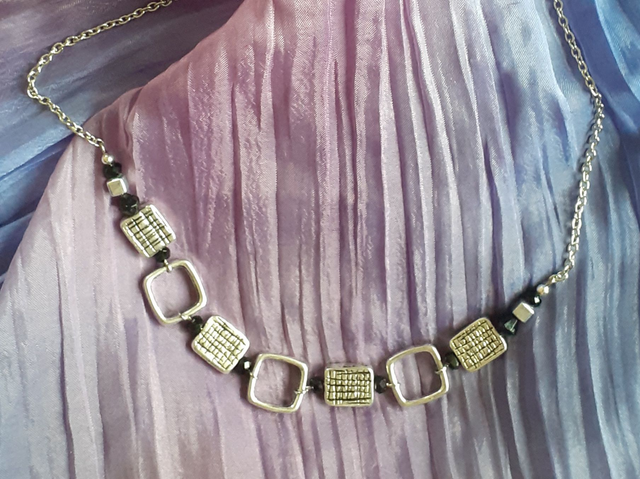 Collier Court argenté, petites perles noires et pièces métalliques.