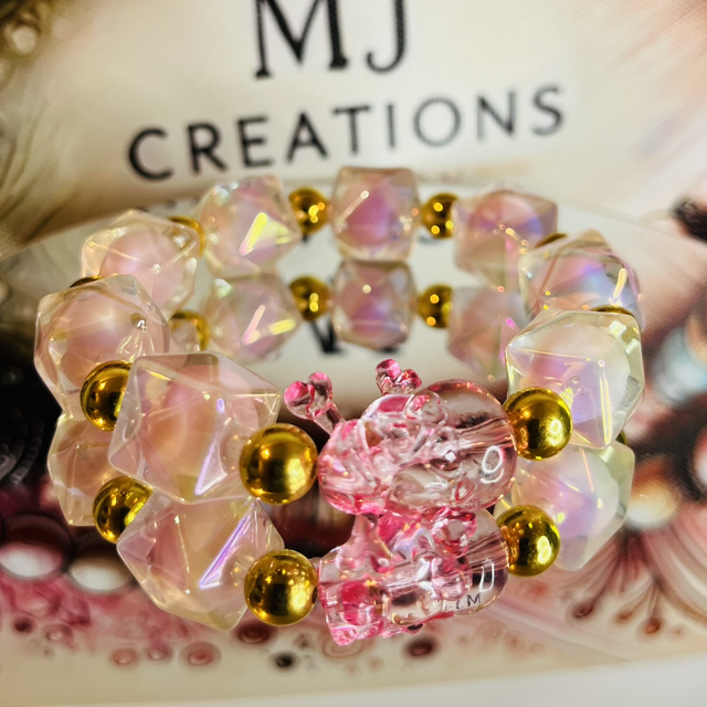 Roze Crystal Skull Charm armband – handgemaakte stretcharmband met iriserende kralen, gouden accenten en roze skull bedel 