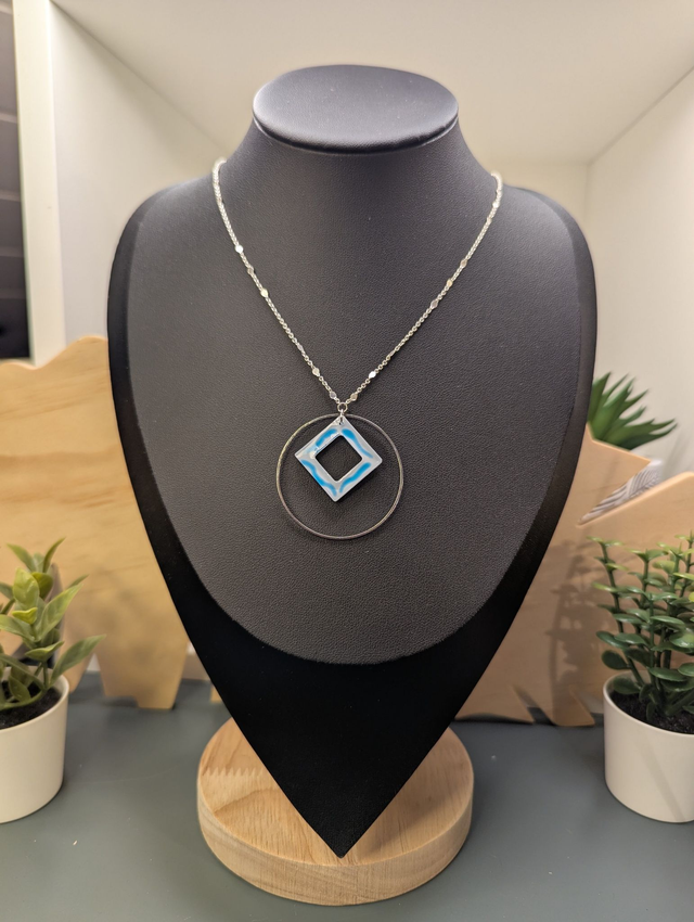 Collier court avec une chaine de couleur argent, un pendentif avec carré en résine et un cercle en métal argenté. 