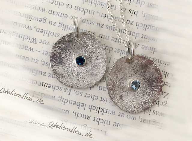 Anhänger „Life isn‘t really round“ aus Silber mit Edelsteinen in verschiedenen Farben.